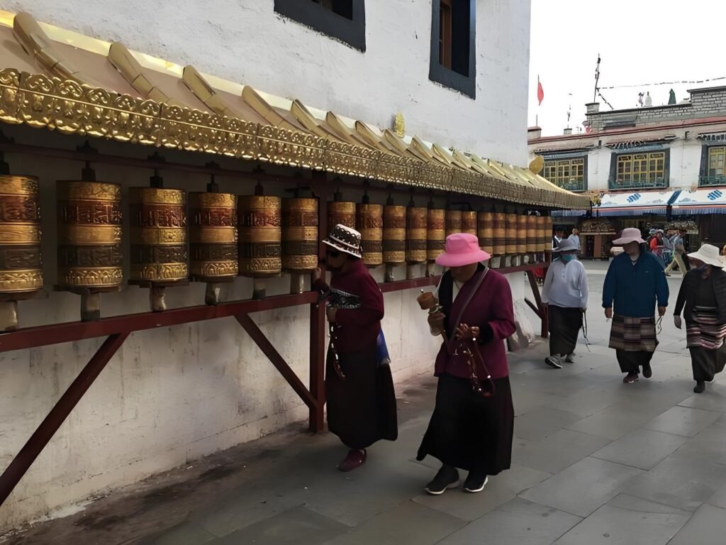 Tibetan pilgrims performing a sacred Kora ritual while spinning traditional brass prayer wheels